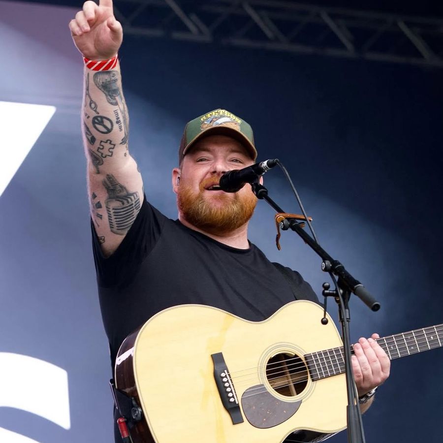 Cammy Barnes performing on stage with an acoustic guitar